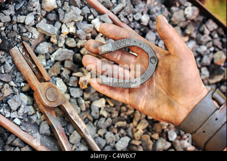 Detail der schmutzigen Hände halten Hufeisen - Schmied Stockfoto