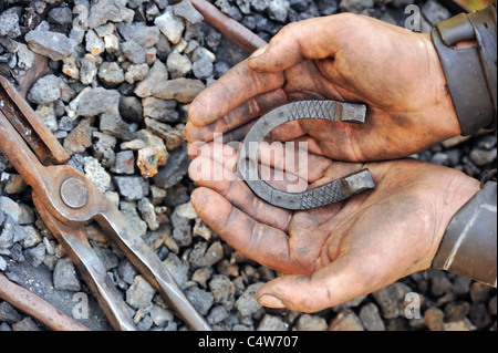 Detail der schmutzigen Hände halten Hufeisen - Schmied Stockfoto