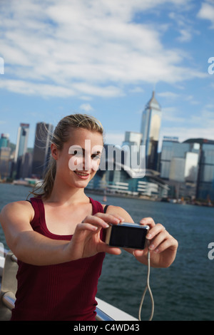 Frau nehmen Foto von sich selbst vor der Skyline von Hong Kong, Hong Kong, China Stockfoto