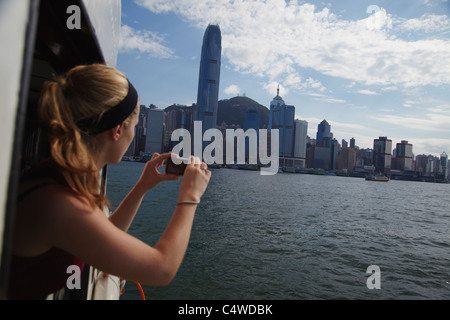 Frau nehmen Foto Skyline von Hong Kong aus Star Ferry, Hongkong, China Stockfoto