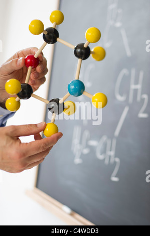 Nahaufnahme des Mannes Hände halten Molekül Modell, Tafel im Hintergrund Stockfoto