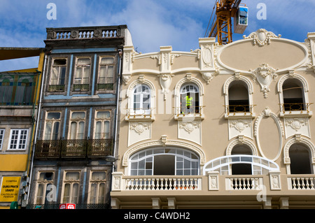 Ein Baumeister, Einbau eines Fensters in ein neues Gebäude in Porto.  Wenig Sicherheit und Gesundheit. Weitwinkel mit Kran. Stockfoto