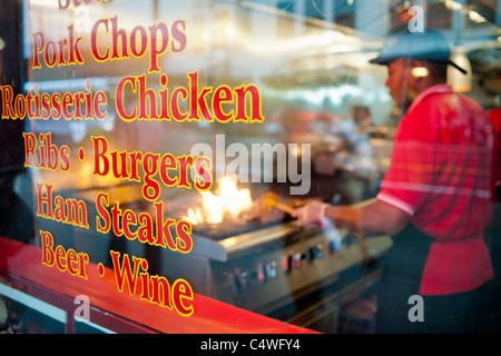 Ein Koch bereitet Steaks auf dem Grill im Fenster des TADS gebratene Steaks in Midtown Manhattan in New York Stockfoto