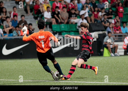 Heirul Suhanes von Singapur U15 geht, um den Ball vor die eingehenden Leonardo Poubel während des 23. Canon Lion Cup zu klären Stockfoto