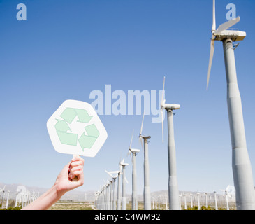 USA, California, Palm Springs, zarte Frauenhand mit recycling Schild gegen blauen Himmel und Wind Turbinen Stockfoto