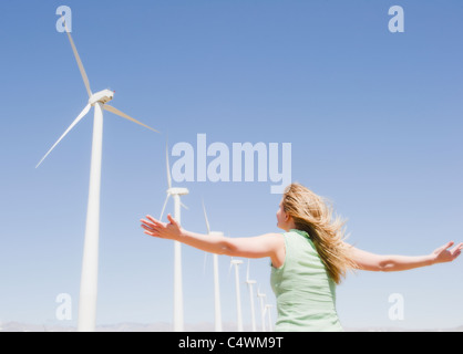 USA, California, Palm Springs, Coachella Valley, San Gorgonio Pass, Rückansicht Frau streckte Arme und Blick auf Windkraftanlagen Stockfoto