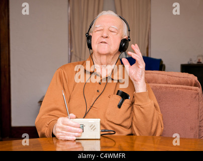 Ein ehemaliger Senior Senior Radio mit Kopfhörern zu hören. Stockfoto
