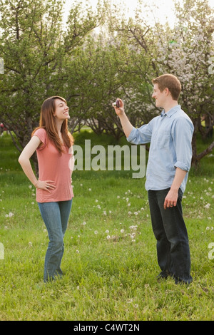 USA, Utah, Provo, junger Mann fotografiert junge Frau im Obstgarten Stockfoto