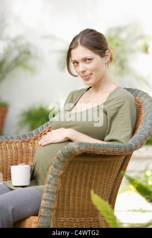 USA, California, Los Angeles, schwangere Frau sitzen im Korbstuhl, berühren, Bauch Stockfoto