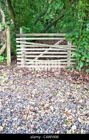 Holzlatte Barriere über ein Gateway. Der Vordergrund ist Stein/Kiesstrand, der Hintergrund ist, Bäume und Sträucher Stockfoto