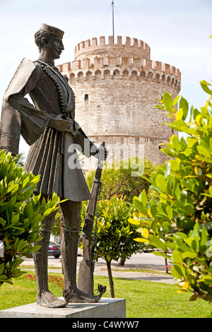 Statue eines Soldaten mit Gewehr und der weiße Turm, ehemals Teil der Stadtmauer und Wahrzeichen der Stadt von Thessaloniki, Griechenland Stockfoto
