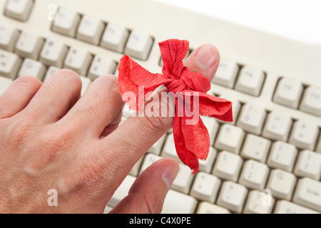 Rote Schleife am Finger und Computer-Tastatur Stockfoto
