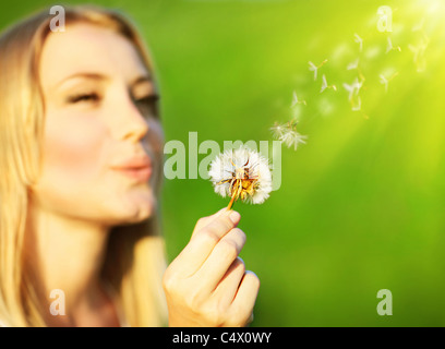 Glücklich schöne Mädchen bläst Löwenzahn, über grüne Natur Hintergrund, Tiefenschärfe, Wunsch-Konzept Stockfoto