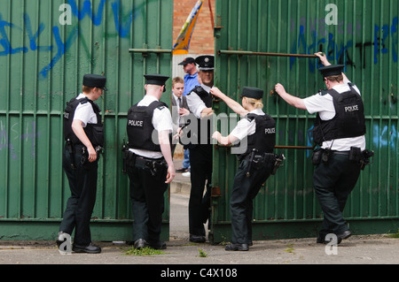 Polizisten öffnen die Tore an die Friedensmauer protestantischen Workman Avenue von der katholischen Springfield Road trennt. Belfast 25.06.2011 Stockfoto