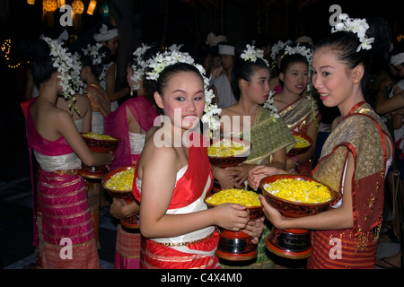 Junge Thai-Frauen in traditionellen Kostümen halten Schalen mit leuchtend gelben Blütenblätter auf einem Festival in Thailand. Stockfoto