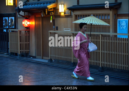 Eine japanische Geisha (Geiko) läuft entlang traditioneller Restaurants im historischen Gion Viertel, Kyoto, Japan JP Stockfoto