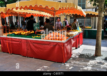 Eine bunte rote doppelseitige Marktstand verkaufen frisches Obst, die von der Sonne geschützt ist, von einem großen gelben Baldachin, Toulon Stockfoto