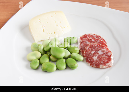 Dicke Bohnen mit Pecorino-Käse und Salami-Scheiben auf einem weißen Teller Stockfoto