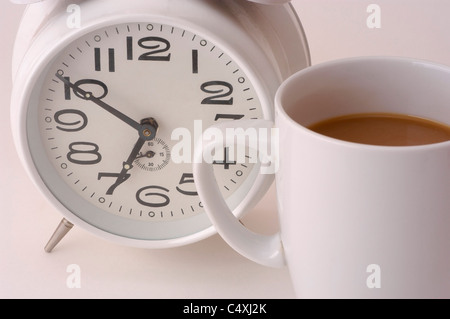 Wecker und Kaffeetasse auf weiß Stockfoto