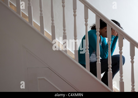 Junge Frau sitzt allein auf Treppe die Hände auf den Kopf. Stockfoto