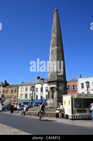 Ein Mann Zyklen hinter dem Obelisken in Richmond Marktplatz, North Yorkshire, England, UK Stockfoto