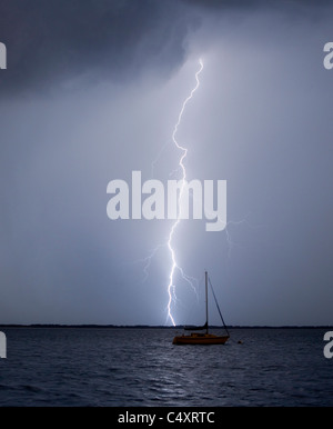 Ein Blitzeinschlag in der Nähe von einem festgemachten Segelboot. Stockfoto