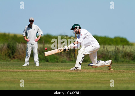 Schlagmann einen Schuss zu spielen, während ein Feldspieler schaut. Stockfoto