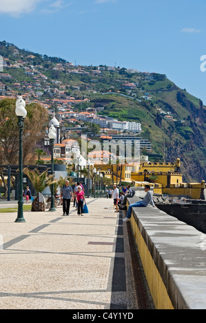 Menschen Touristen Besucher zu Fuß entlang der Strandpromenade mit Forte De Sao Tiago im Hintergrund Funchal Madeira Portugal EU Europa Stockfoto