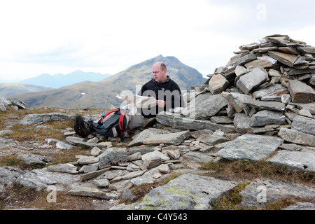 Mann, Blick auf eine Karte auf dem Gipfel des Ben Oss mit Ben Lui im Hintergrund Stockfoto