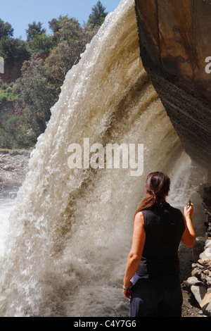 Weibliche Wanderer Abkühlung mit Spray vom Wasserfall auf dem Fluss Guadalfeo in der Nähe von Orgiva in La Alpujarra, Andalusien, Spanien Stockfoto