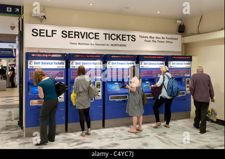 Reisende, die Karten von automatisierten Fahrkartenautomaten am Bahnhof Leeds, England kaufen. Stockfoto