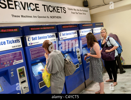 Reisende, die Karten von automatisierten Fahrkartenautomaten am Bahnhof Leeds, England kaufen. Stockfoto