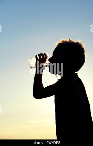 Junge aus Plastikbecher Mineralwasser trinken. Silhouette Stockfoto