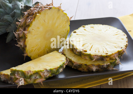 Geschnittene Ananas auf einem braunen Teller serviert. Stockfoto