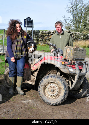 Bauer und Frau mit Schäferhund und Quad-Bike machen Sie eine Pause vom Schaf aufrunden zu posieren für Fotos an Corsenside, UK Stockfoto