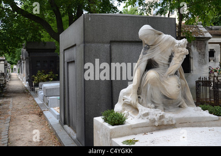 Die Statue einer Frau in Trauer legt Blumen auf ein Grab im Friedhof Montmartre, Paris, Frankreich. Stockfoto