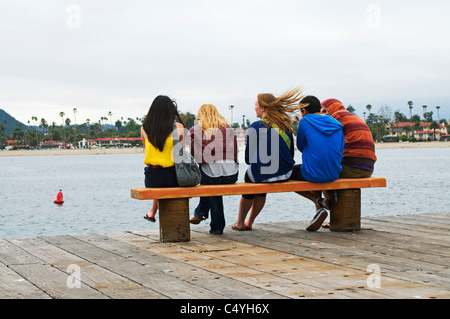 Gruppe von Jugendlichen sitzen auf Bank in der Nähe von Meer Stockfoto