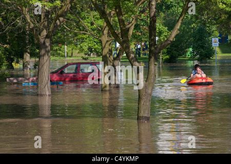 Männer in Ponton paddeln über überfluteten Parkplatz in der Nähe von Wohnhaus, 2010 Flut an Kozanow von Wrocław, Polen Stockfoto