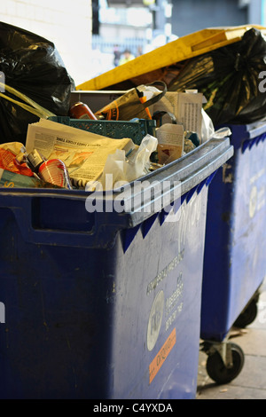 Zwei kommerzielle Wheelie Eimer voller Müll in hellem Sonnenlicht Stockfoto