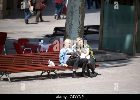 Ältere Ehepaare, die sich entspannen und auf einer Sitzbank auf den Straßen von Barcelona Spanien sitzen. Stockfoto
