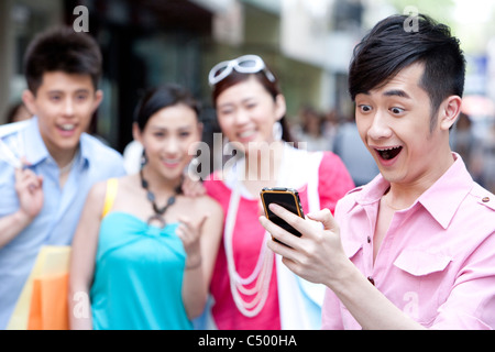 Junger Mann mit Handy vor Freunden Stockfoto