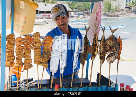 Ein Mann verkauft frische, leckere gegrillte Garnelen und Fisch von einem Push-Karren am Strand in Rincon de Guayabitos, Nayarit, Mexiko. Stockfoto