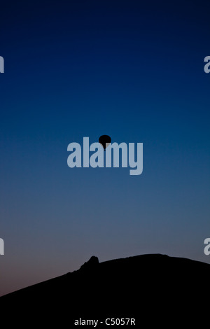 Heißluftballon Silhouette gegen ein Abendhimmel über dem Gaerstone Felsen, auf Hope Bowdler Hügel in der Nähe von Kirche Stretton Stockfoto