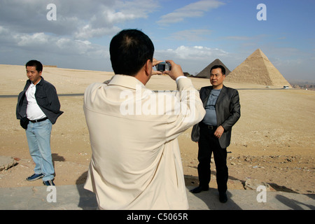 Touristen bereiten und Fotografieren mit den Pyramiden von Gizeh als Kulisse. Kairo, Ägypten. Stockfoto