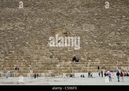 Touristen stehen an der Basis der großen Pyramide von Khufu, unten der Eingang zur Königskammer in Gizeh, Kairo, Ägypten Stockfoto