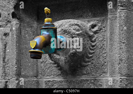 Gelb und blau Wasserhahn auf einer Steinmauer Stockfoto