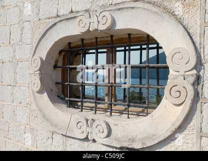 verzierten geschnitzten historischen natürlichen Stein Fenster mit einer bergigen Bucht in ihm reflektiert Stockfoto