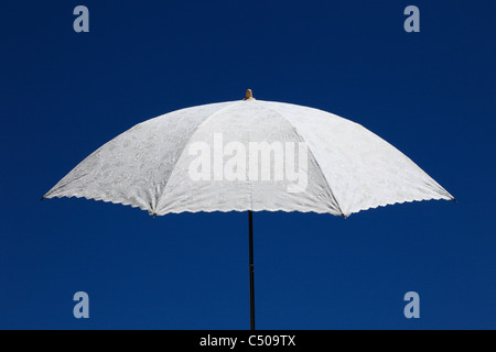 Ein Hand gehaltenen weißen Leinen Sonnenschirm mit gestickten Details, legen Sie gegen einen klaren, blauen Sommerhimmel. (Hochformat Ref C509TF) Stockfoto