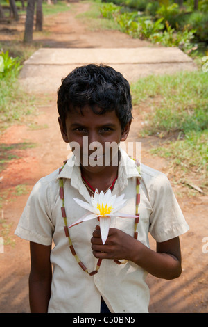 Ein Junge hielt eine Lotusblüte in den Backwaters von Kerala in Kollam, Indien. Stockfoto