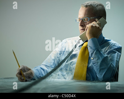 Kaukasische Geschäftsmann bedeckt in Spinnweben am Telefon sprechen Stockfoto